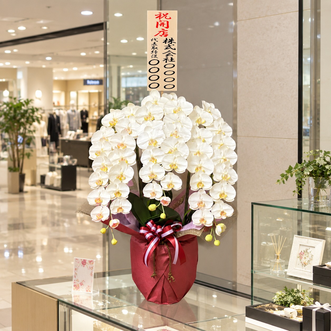 開店祝の立札を付けた光触媒造花胡蝶蘭・特大輪3本立ち(白)・ホワイト化粧鉢をショッピングセンターに設置したイメージ画像